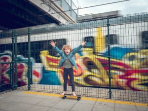 Preteen boy on skateboard screaming against passing train